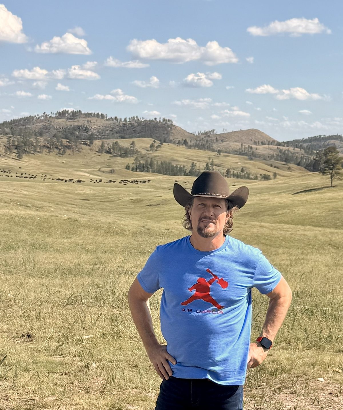 Justin in a cowboy hat in front of a bison herd in the Black Hills