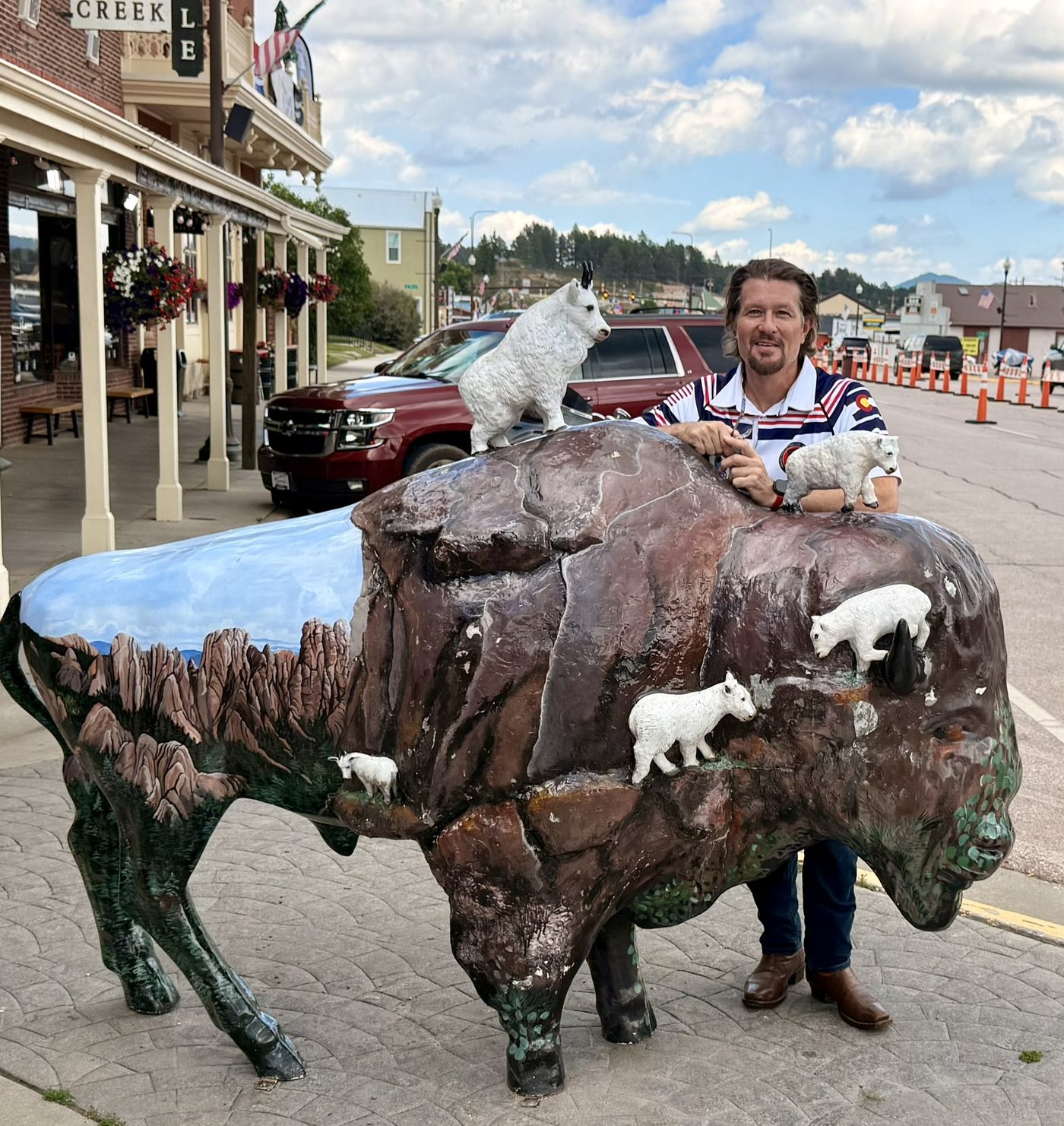 Justin behind a painted bison sculpture on a small-town main street