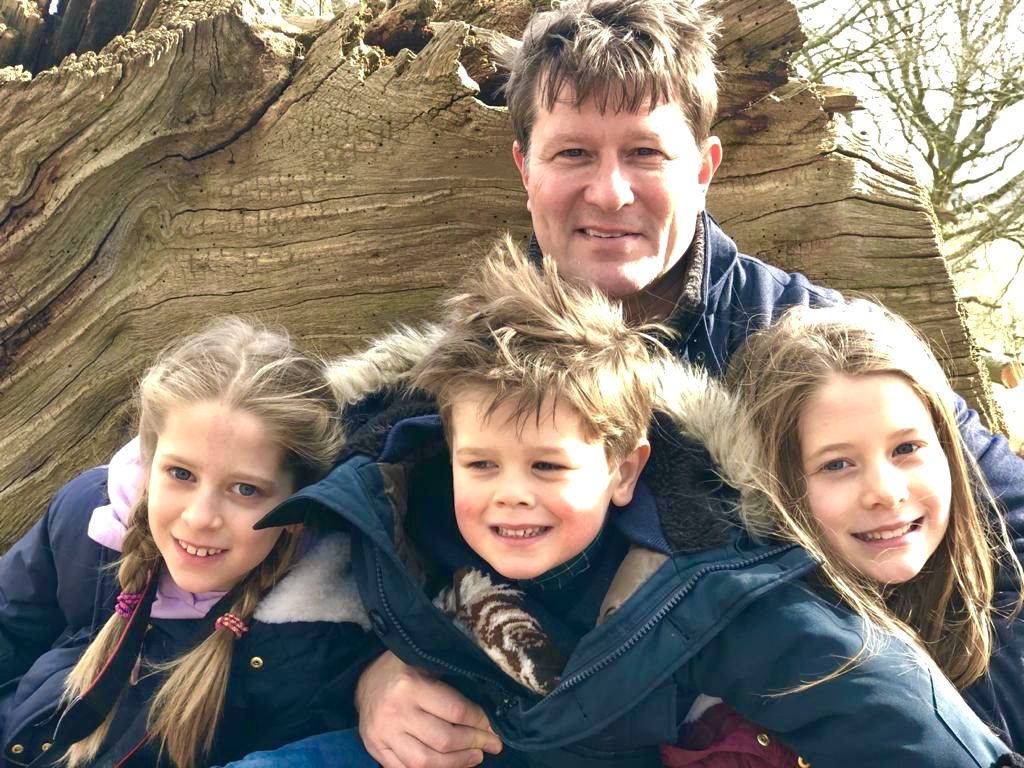Justin with his three children in front of a fallen tree